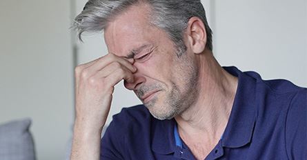 man touching nose because of sinus pain